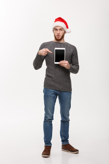 Holiday and Business Concept Young handsome man showing tablet display and pointing finger presenting