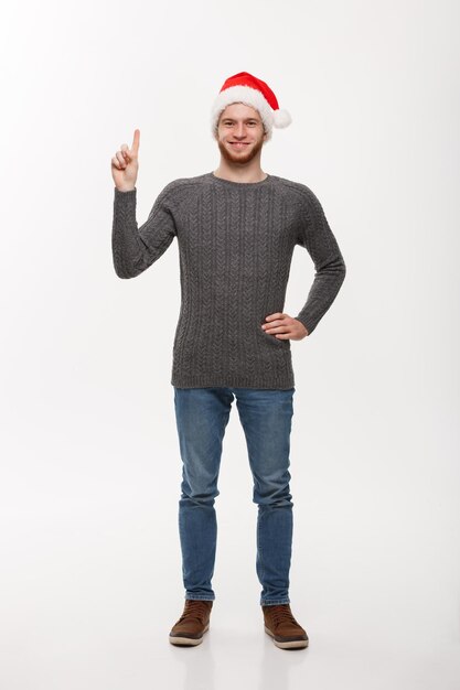Holiday Concept Young beard man in sweater enjoy playing and pointing finger upward