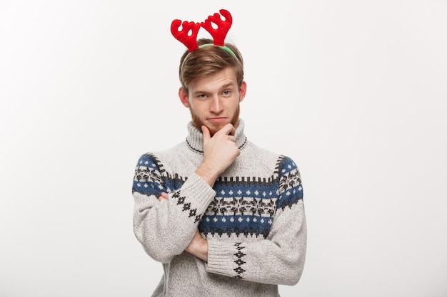 Free photo holiday concept young beard man in sweater with thoughtful gesture on white background