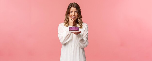 Holidays spring and party concept alarmed worried young blond girl hesitating eat cake or not being