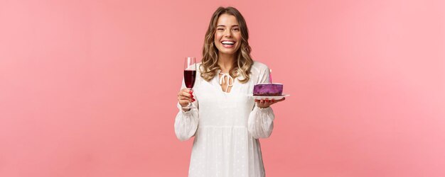 Holidays spring and party concept Portrait of excited goodlooking young tender girl celebrating birthday having fun with friends eating bday cake and drink wine from glass laughing joyfully