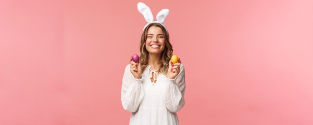 休日の春とパーティーのコンセプト家族と一緒にイースターを祝う色の卵を保持しているウサギの耳に素敵な陽気なブロンドの女の子の肖像画は、親しい人々と伝統的な一日を過ごします
