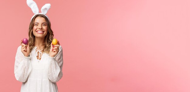 Holidays spring and party concept Portrait of lovely cheerful blond girl in rabbit ears holding colored eggs celebrating Easter with family enjoying spend traditional day with close people