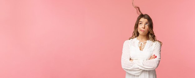 Holidays spring and party concept Portrait of troubled busy young blond girl over pink background trying blew away annoying hair strand from face blow at hair look up stand pink background