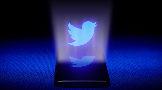 Twitterのロゴの光沢のあるバッジを持っている手 プレミアム写真 Twitterのロゴの光沢のあるバッジを持っている手 プレミアム写真