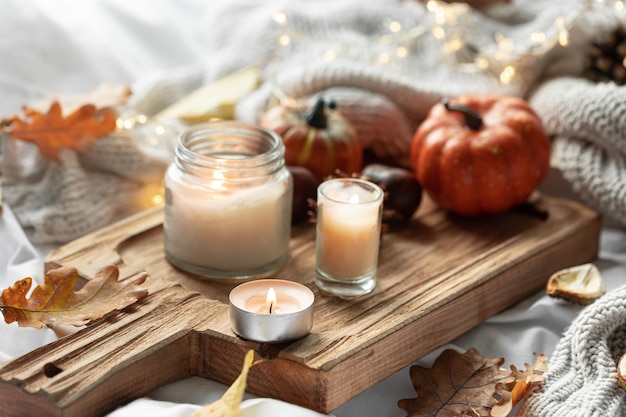 Home autumn composition with candles leaves and knitted element