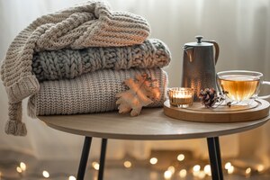 Composizione autunnale domestica con tè e maglioni lavorati a maglia all'interno della stanza, su uno sfondo sfocato con una ghirlanda.