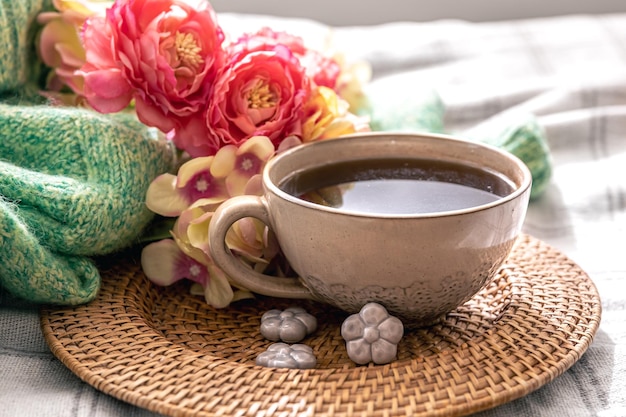 Home composition with a cup of tea flowers and a knitted element in the bed