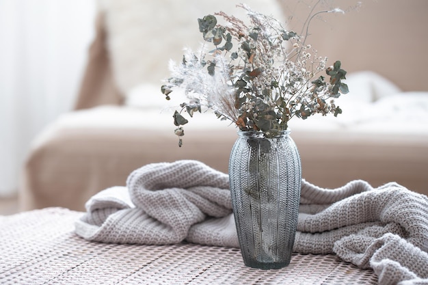 Composizione domestica con un vaso di vetro con fiori secchi su sfondo sfocato