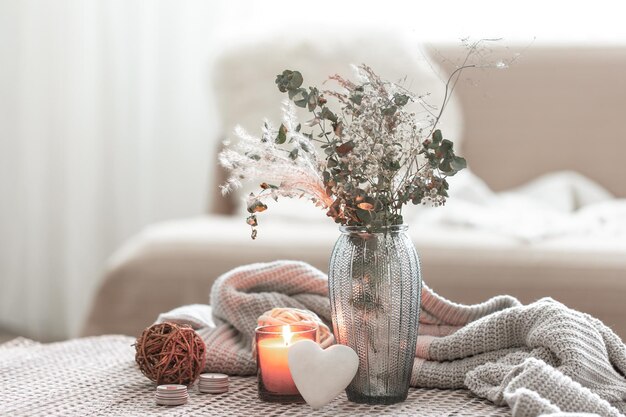 Home composition with a glass vase with dried flowers and a decorative heart