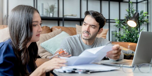 家の財政の夫と妻は、多くの問題と借金の家のインテリアの背景とストレスと混乱した気持ちと一緒に紙幣の領収書について話し合っています
