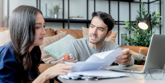 Home financehusband and wife discussing paper bill receipt together with stress and confused feeling with many problem and debt home interior background