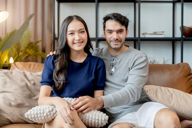 家の隔離の概念幸福アジアと白人の愛のカップル家族リビングルームのソファソファでの良い会話結婚カップルはソファで一緒に笑顔を笑う