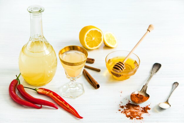 Домашняя настойка красного перца в стакане и свежие лимоны на деревянный стол