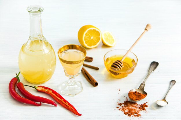 Home red pepper tincture in a glass and fresh lemons on wooden table