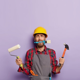 Operaio maschio riparazione casa impegnato con ristrutturazione casa, detiene attrezzature da costruzione