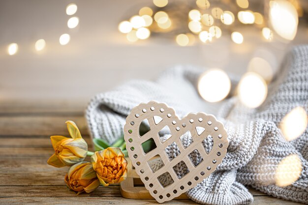 Home romantic still life with wooden decorative heart and knitted element on blurred background with bokeh.