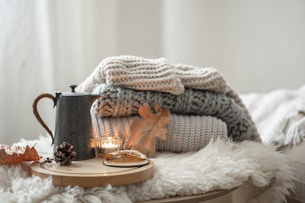 Free photo home still life with knitted sweaters and teapot of tea on blurred background.