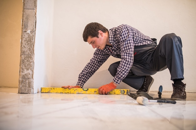 Free photo home tile improvement - handyman with level laying down tile floor