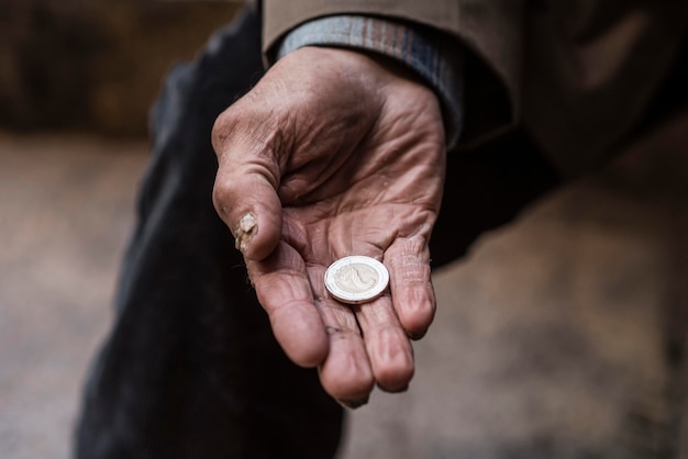 Homeless man holding coin in his hand