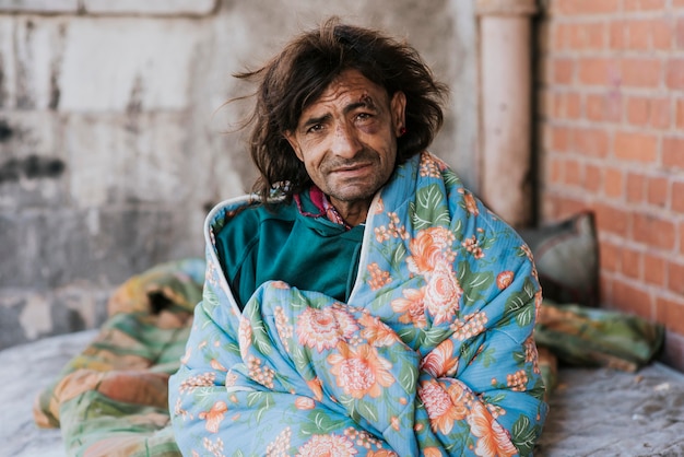 Foto gratuita uomo senza casa all'aperto sotto coperta
