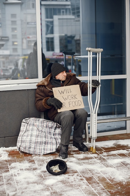 Free photo homeless sitting near building.