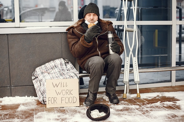 Free photo homeless sitting near building.