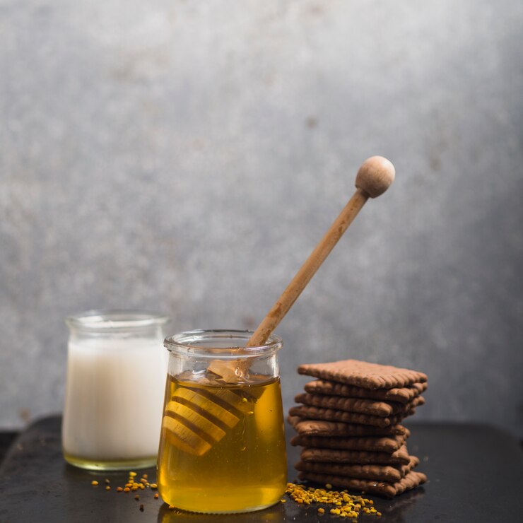 Free Photo homemade biscuits stack; milk and honey pot with honey dipper