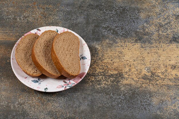 Homemade black bread sliceson colorful plate