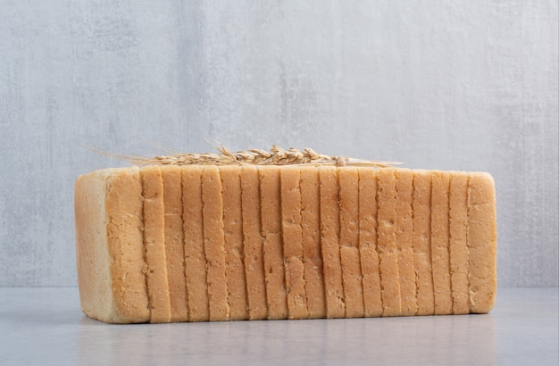 Free photo homemade bread slices on stone surface with wheat