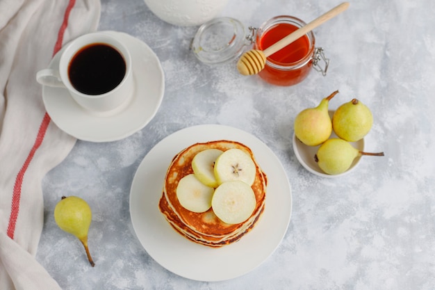 Домашний завтрак: блинчики по-американски с грушами и медом, чашка чая на бетоне. вид сверху и копия