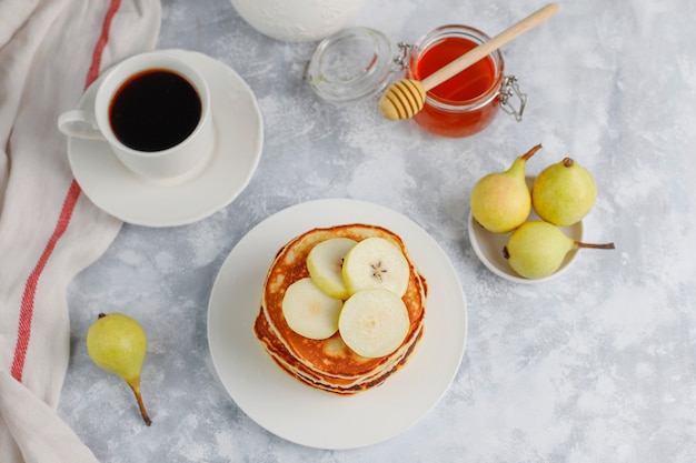 Colazione fatta in casa: frittelle all'americana servite con pere e miele con una tazza di tè sul cemento. vista dall'alto e copia