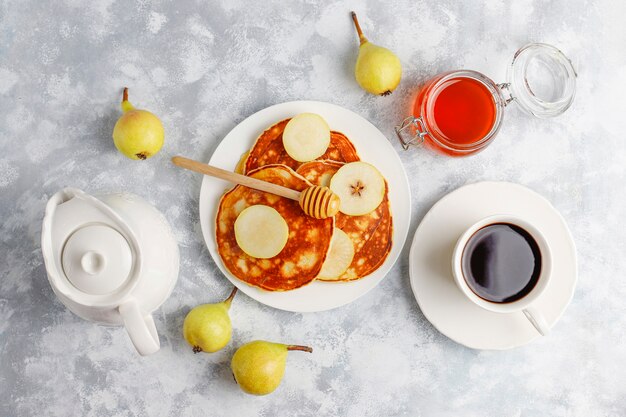 Homemade breakfast: american style pancakes served with pears and honey with a cup of tea on concrete . Top view and copy 