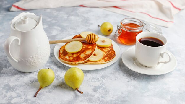 Homemade breakfast: american style pancakes served with pears and honey with a cup of tea on concrete . Top view and copy 