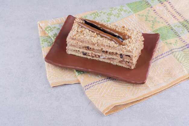 Homemade cake on brown plate with tablecloth.