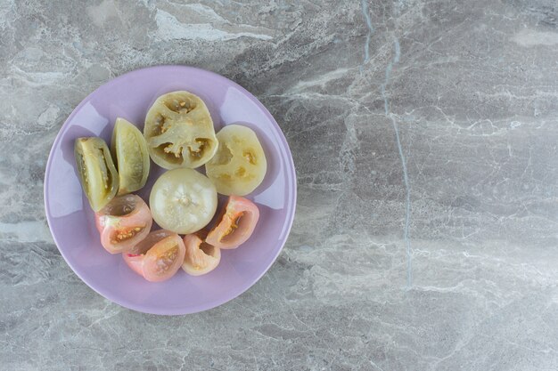 보라색 접시에 집에서 만든 통조림된 토마토 조각입니다.