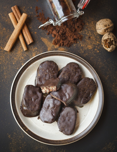 Barrette di cioccolato fatte in casa con noci, cacao e cannella in un piatto bianco su una superficie nera