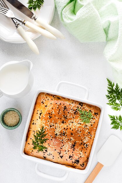 白いコンクリートの背景に野菜と自家製の閉じたパイ テーブルの上のキャベツとニンジンのパイの材料