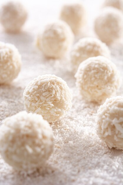 Homemade coconut balls on white wooden table