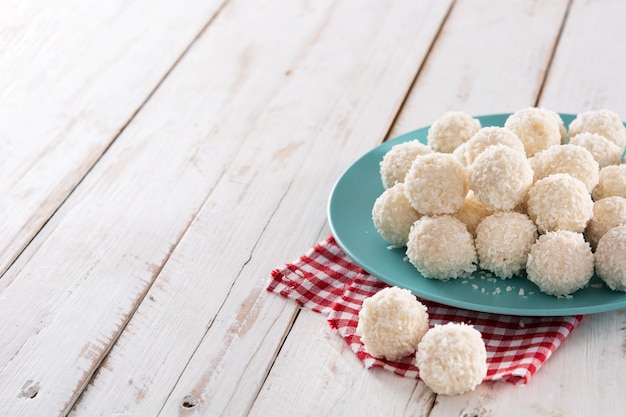 Homemade coconut balls on white wooden table