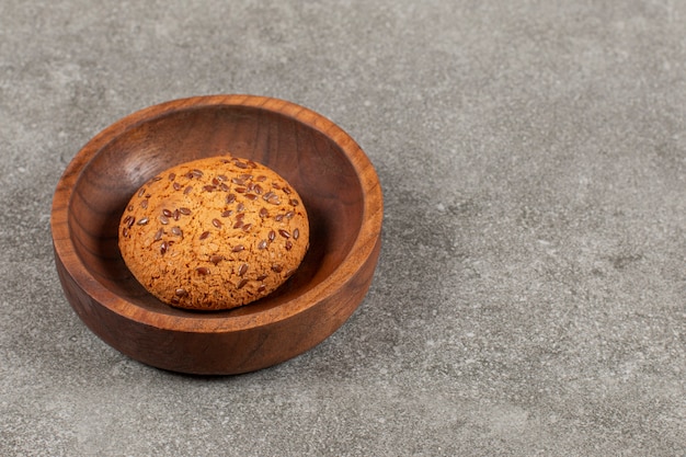 Homemade cookie in wooden bowl over grey.