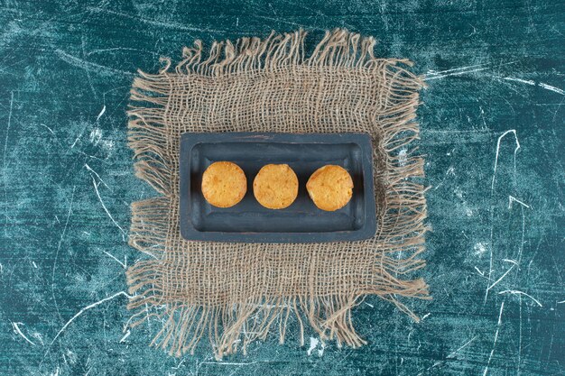 Бесплатное фото Домашнее печенье на деревянной тарелке на полотенце, на синем фоне. фото высокого качества
