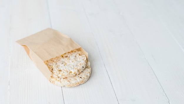 Riso soffiato croccante fatto in casa in sacchetto di carta marrone sullo scrittorio di legno bianco