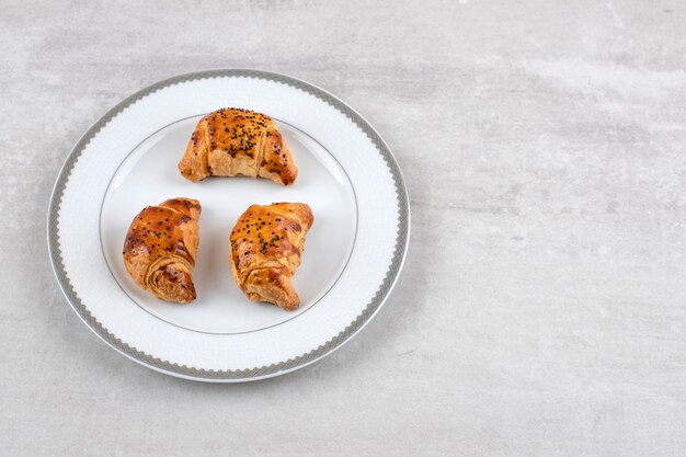 Homemade croissants on a board, on the marble table. 