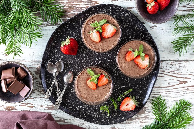 Homemade delicious chocolate mousse or panna cotta with berries on a white stone or wooden background Festive dessert