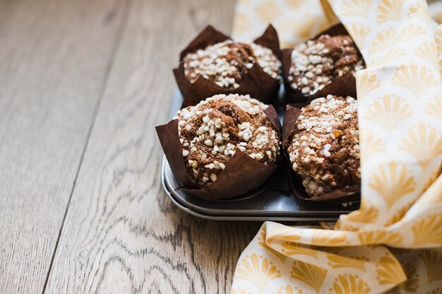 ベーキングトレイに茶色の紙で自家製のおいしいチョコレートのマフィン