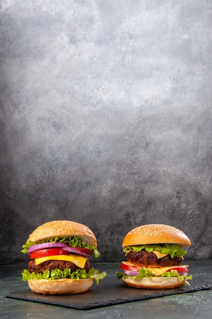 Homemade delicious sandwiches on black board on dark gray blurred surface in vertical view