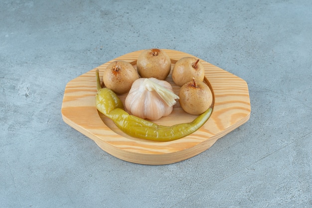 Homemade fermented vegetables on a wooden plate on the marble surface