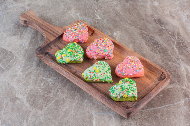 Homemade fresh cookies in heard shape on wooden board.