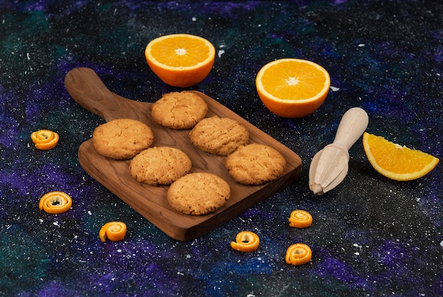 Free photo homemade fresh cookies on wooden chopping board and half cut oranges.